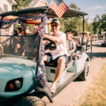 Man driving decorated golf cart in Carlton Landing Fourth of July parade